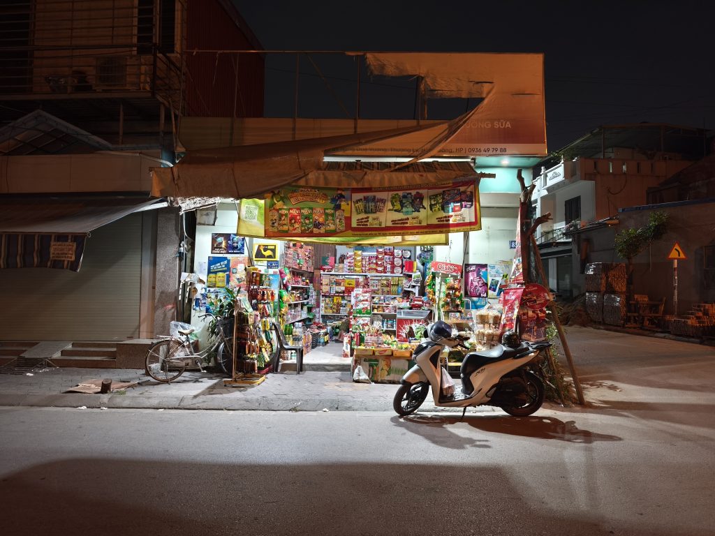 Nachtszene in Haiphong, Vietnam: Vor einem Shop steht ein Moped